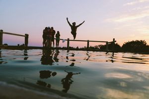 Jumping into the pool: man jump in mid air on body of water